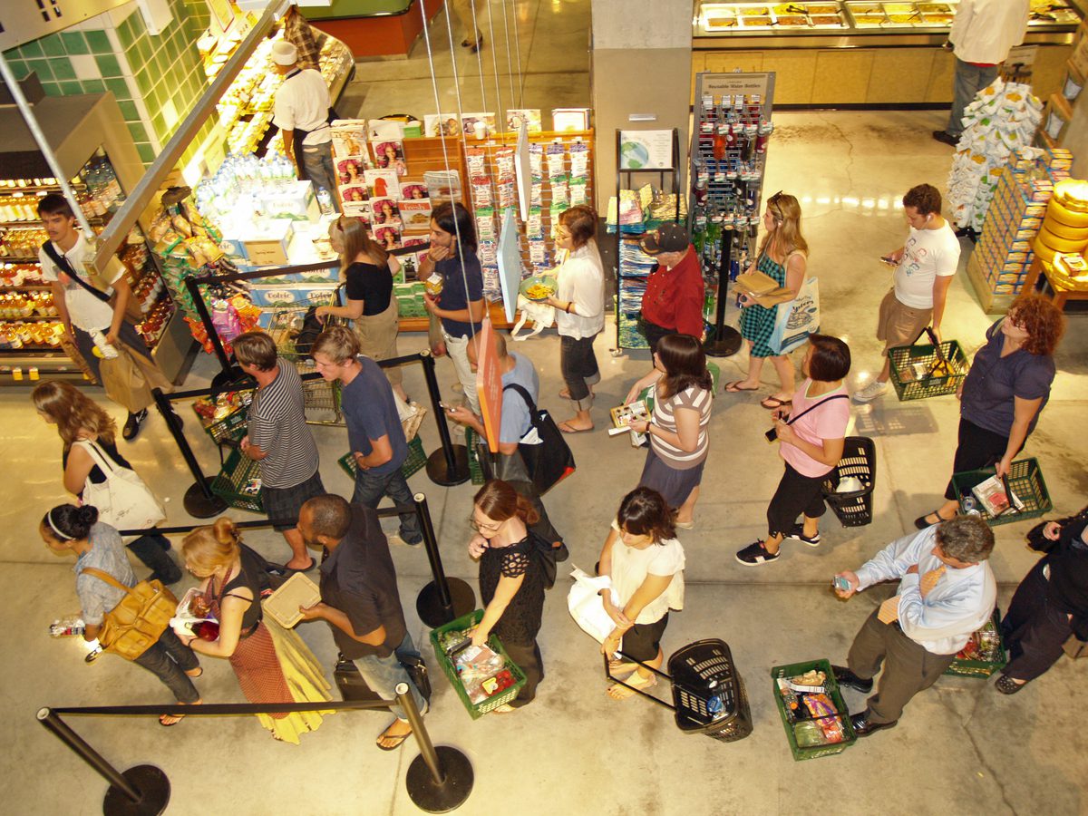 Busy grocery store checkout queue seen from overhead security camera